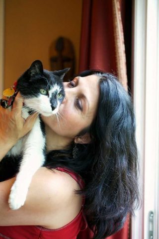 Pet photography of a woman kissing her cat on the face.