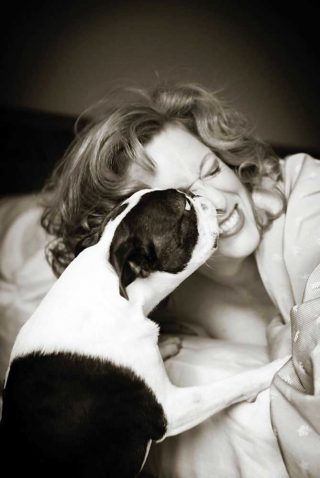 A candid black and white photo of a woman and her Boxer dog taken by pet photographer Trina Koster.
